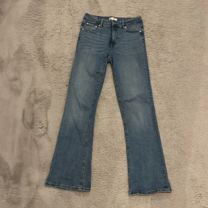 Blå bootcut jeans - Snygga blå bootcut jeans med klassisk femficksdesign och knappgylf. Perfekta för en avslappnad stil med en touch av retro. Passar bra till både sneakers och klackar.Lite stor i storlek,men ändå så är de super fina ☺️