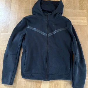 Svart hoodie från Nike - Säljer en svart hoodie från Nike med dragkedja och huva. Den har en diskret logga på bröstet. Barn storlek xl (158-170 cm) 
