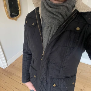 Marinblå quiltad jacka från Barbour - Snygg mörkblå quiltad jacka från Barbour. Knappen näst högst upp vid dragkedjan är borta (kommer aldrig till användning ändå), och annars är jackan i riktigt fint skick! Passar som en S. 
