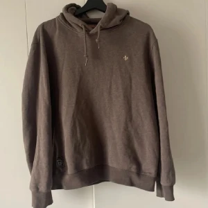 Brun hoodie från Morris - Säljer en snygg brun hoodie från Morris. Den har en klassisk design med justerbar huva och ribbade muddar. Perfekt för en avslappnad stil. Märkeslogga syns diskret på bröstet och nederkanten. Vid snabb affär kan priset gå ner mycket 
