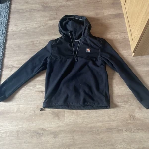 Svart fleecejacka från Ellesse - Säljer en svart fleecejacka från Ellesse med huva och dragkedja. Jackan har en mjuk insida och är perfekt för kyligare dagar. Den har en liten logotyp på bröstet och är i storlek S.😁