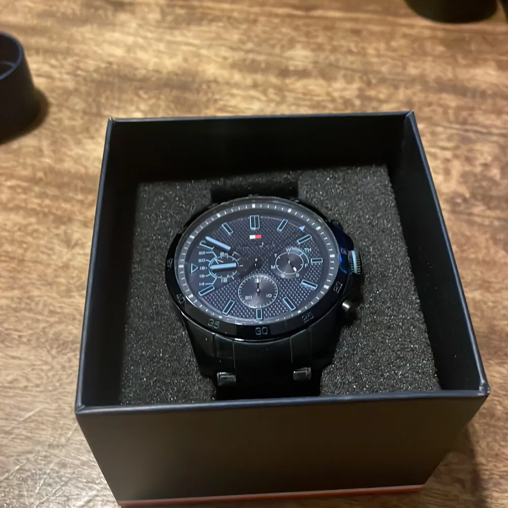 Snygg svart klocka från Tommy Hilfiger med flera urtavlor och en stilren design. Klockan har en svart länkarmband och tydliga markeringar på urtavlan. Perfekt för den som vill ha en elegant och funktionell accessoar. Tyvärr funkar den dessvärre inte vet inte varför förmodligen pga batteriet. därav det billiga priset. Ny pris 2800kr.. Asusteet.
