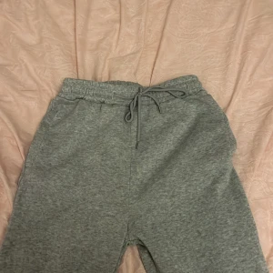 Grå mjukisbyxor med dragsko - Säljer ett par grå mjukisbyxor med elastisk midja och dragsko för justerbar passform. Perfekta för en avslappnad stil. Har två i dessa byxor. Ena är stl xs och har en liten fläck medans andra är stl s och är lite längre i benen, perfekt för kalla dagar. Pris kan diskuteras