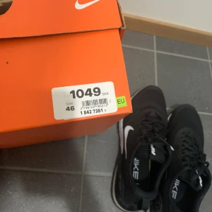 Svarta Nike sneakers - Säljer ett par svarta Nike sneakers med vit sula och klassisk Nike-logga. Skorna har snörning och en bekväm passform, perfekta för vardagsbruk. Nyköpta från nike.com, beställde tyvärr fel storlek. Bara växjö!