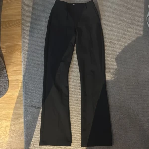 Svarta kostymbyxor - Snygga svarta kostymbyxor med en elegant och klassisk design. Byxorna har en rak passform och är perfekta för en stilren look. De är tillverkade i ett mjukt och bekvämt material.