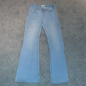 Ljusblå jeans från Lindex - Säljer ett par ljusblå jeans från Lindex i storlek 152. De har en bootcut-stil och är perfekta för en avslappnad look. Tillverkade i ett mjukt denimtyg.
