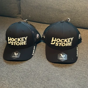 Svart keps från Bauer - Säljer två styckna Bauer hockeystore kepsar. Har aldrig använt dom och vill bli av med dom. Lapparna och klistermärket på skärmen sitter kvar på båda. OBS!! PRISET PÅ ANNONSEN ÄR FÖR EN KEPS!