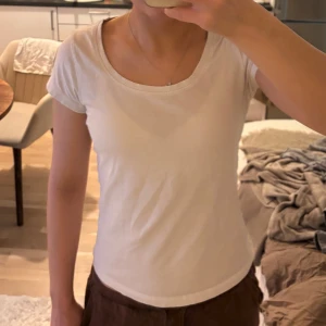 Vit kortärmad t-shirt - Säljer en enkel och stilren vit t-shirt med korta ärmar. Perfekt basplagg för alla tillfällen. T-shirten har en rund halsringning och är gjord i ett mjukt material.