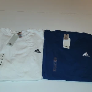 Vit och blå t-shirt från Adidas - Säljer två snygga t-shirts från Adidas i storlek XL. En är vit och den andra är blå, båda med Adidas-loggan på bröstet. Perfekta för en sportig look eller avslappnad stil. Helt nya med taggar kvar! Säljer för jag köpte fel storlek en för 200 båda för 350