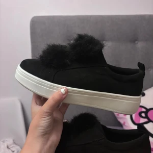 Svarta sneakers med pälsdetalj - Snygga svarta sneakers med en unik pälsdetalj på ovansidan. Skorna har en vit sula som ger en fin kontrast till det svarta. Perfekta för att ge din outfit en trendig touch.