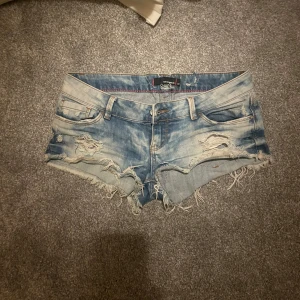 Blå Lågmidjade jeansshorts  - Säljer ett par snygga blå lågmidjade jeansshorts från Tally Weijl. Ända defekten är att det är små hål vid midjan i insidan av shortsen, men inget som stör hur dom passar! 💕