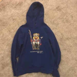 Blå Polo Bear hoodie RALPH LAUREN  - Säljer en snygg blå Polo Bear hoodie från Ralph Lauren i barnstorlek L/G (14–16 år). Den är i nyskick, knappt använd och utan några defekter 9/10 i skick. Ny pris 1300kr. Hör av dig vid frågor eller om du vill köpa. Först till kvarn!