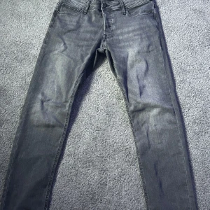 Grå jeans från Jack & Jones - Snygga grå jeans från Jack & Jones, modell Slim/Glenn. De har en slim passform och är tillverkade i ett bekvämt material. Perfekta för en stilren look.