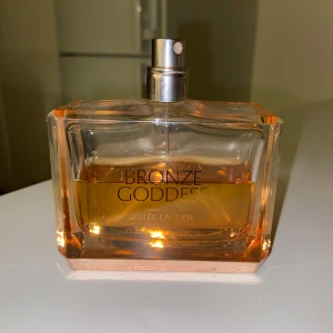 Bronze Goddess Eau de Parfum Estée Lauder 100 ml - Säljer denna diskade version av Bronze Goddess Eau de Parfum från Estée Lauder. Flaskan rymmer 100 ml och är mer än hälften kvar.                                       🔝Topp: Mandarin,italian bergamot, ginger extract.     ❤️Hjärta: indian Jasmine, sambac absolute, creamy coconut & frangipani petals.                                       🅱️Bas: vanilla absolute, cashmere Wood, captive musk & Amber. 
