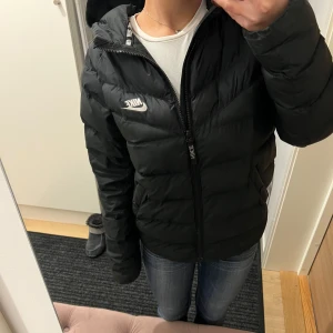 Svart dunjacka från Nike - Säljer en svart dunjacka från Nike då den inte kommer till användning längre. Jackan är i bra skick och jag skulle säga att den passar en XS/S. 