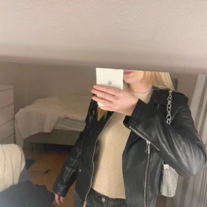 Svart skinnjacka med dragkedjor - Snygg svart skinnjacka med flera dragkedjor och klassisk bikerstil. Även hittat ett bälte som tillhör jackan!