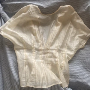 Vit blus med korta ärmar - Elegant vit blus med korta ärmar och lös passform. Tillverkad i ett lätt och luftigt material, perfekt för varmare dagar. Blusen har en rund halsringning och ett enkelt men stilrent utseende.