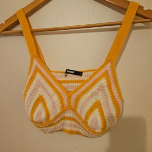Randig stickad topp från BikBok - Säljer en färgglad stickad topp från BikBok i storlek S. Toppen har ett randigt mönster i gult, vitt och rosa med breda axelband. Perfekt för en somrig look!