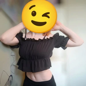 Svart offshoulder topp - Snygg svart offshoulder topp med volangdetaljer. Perfekt för en trendig look. Toppen har en luftig passform och är tillverkad i ett lätt material.