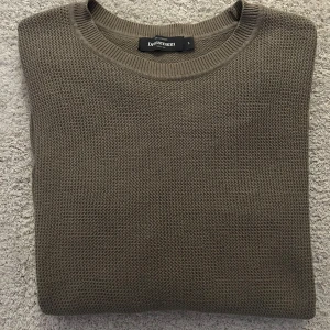 Olivgrön stickad tröja från Dressman - Säljer en stilren olivgrön stickad tröja från Dressman. Tröjan har en rund halsringning och är perfekt för kyligare dagar. Den är mjuk och bekväm, idealisk för både vardag och avslappnade tillfällen.