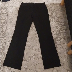 Svarta kostymbyxor från BikBok - Snygga svarta kostymbyxor från BikBok i storlek 40. Byxorna har en klassisk design med raka ben och hällor för bälte. Perfekta för en stilren look.