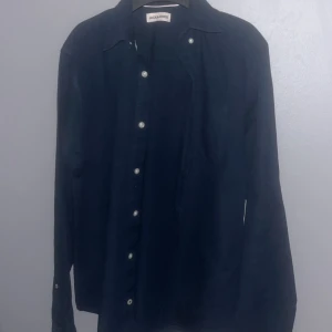 Svart skjorta från Jack and Jones - Elegant svart skjorta från Jack and Jones med klassisk krage och knappar framtill. Skjortan har långa ärmar och en stilren design som passar perfekt för en sofistikerad look.