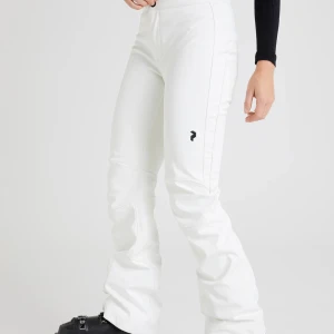 Vita byxor med bootcut - Säljer ett par vita skidbyxor med normal midja och bootcut-stil. Använt 2 skidsemstrar och säljer nu i bra skick. De är lite nötta och det finns  lite smuts som inte syns på långt håll. Jätte fina, vattentäta och vindtäta. Nypris: 3000kr
