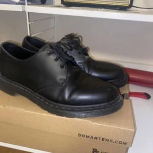Svarta Dr. Martens 1461 Mono - Säljer ett par klassiska svarta Dr. Martens 1461 Mono i skinn. Skorna har en stilren design med snörning och en robust sula. Perfekta för både vardag och mer formella tillfällen.