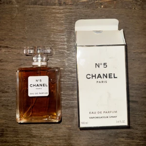 Chanel No. 5 Eau de Parfum - Elegant och tidlös parfym från Chanel i en klassisk glasflaska med en stilren vit etikett. Doften är ikonisk och sofistikerad, perfekt för den som vill ha en touch av lyx. Flaskan rymmer 100 ml och kommer med förpackning. Fått av min vän i julklapp, hon köpte parfymen på Bali.