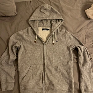 Grå hoodie från Morris - Säljer en stilren grå hoodie från Morris med dragkedja och justerbar luva. Tröjan har långa ärmar och praktiska fickor framtill. Perfekt för en avslappnad look. Pris går att diskutera!🤩