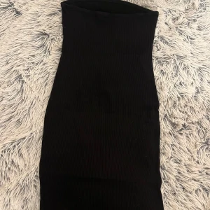 Svart ribbad klänning från Divided - Snygg svart ribbad klänning från Divided. Den är ärmlös och har en tight passform som framhäver figuren. Perfekt för en stilren look.