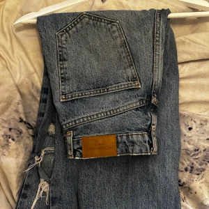 Jeans Ginatricot - Högmidjade mörka blåa jeans från Ginatricot i storlek 32, säljer då de är för små. De har två hål vid knäna och ett litet mindre ovanför ena knät. Har använt de ganska mycket men de är i bra skick! 🩷