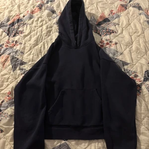 Mörkblå hoodie - Säljer en stilren mörkblå hoodie med en klassisk känguruficka framtill. Perfekt för en avslappnad look. Huvan ger extra mysfaktor och den ribbade nederkanten ger en bra passform.