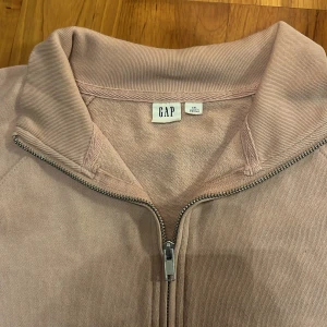 	GAP Ljusrosa Tröja – Perfekt Som Pyjamas - Bekväm ljusrosa GAP-tröja i bra skick. Perfekt att använda både som vardagströja eller som pyjamas-klänning om man har mindre storlek (fungerar som ‘one size’). Den har en hög kvalitet och är väldigt mjuk och skön att bära.