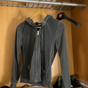 Grå hoodie från Gina Tricot - Säljer en stilren grå hoodie från Gina Tricot i storlek XS. Den har en dragkedja framtill och en praktisk huva. Perfekt för en avslappnad look.