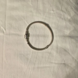 Silverarmband från Pandora - Elegant silverarmband från Pandora med en klassisk ormkedjedesign och ett stilrent lås. Perfekt för att bära som det är eller för att lägga till dina favoritberlocker.