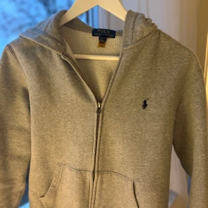 Grå hoodie från Polo Ralph Lauren - Säljer denna sjukt snygga Ralph lauren koftan för bara 369kr! Koftan är i skick 7/10 | På bilden är det en 170cm lång kille som har på sig den | 