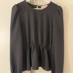 Svart blus med resår i midjan - Elegant svart blus från Only med långa ärmar och en rund halsringning. Blusen har en lätt resår i midja som ger en fin siluett. Perfekt för både vardag och mer uppklädda tillfällen.