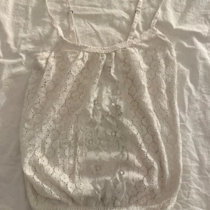 Vit spetslinne från Hollister - Säljer en söt vit spetslinne från Hollister med justerbara axelband. Perfekt för varma sommardagar. Linnet har ett vackert blommönster och elastisk nederkant för en bekväm passform. Skriv privat för fler frågor💕