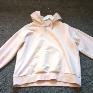 Ljusrosa hoodie från Gina Tricot - Säljer en mysig ljusrosa hoodie från Gina Tricot. Den har en klassisk design med en stor ficka framtill och justerbar huva. Perfekt för en avslappnad stil.