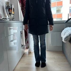 Svart dunjacka från Cedrico - Säljer min stilrena mörkblåa dunjacka från Cedrico i storlek XXS men passar som S. Jackan har en lång passform med huva och dragkedja framtill. Perfekt för kalla dagar med sin varma och skyddande design. Nypris: ca 6000 kr💗