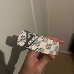 LvBälte   - En vit rutig bälte som är mycket fin med silver på och storlek 125 cm kommer även med en nål som kan göra hål ifall den är liten för dig 