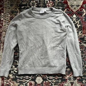 Grå stickad  tröja från VILA - Säljer en grå stickad tröja från VILA. Den är i storlek M, men sitter även snyggt på xs/s, beroende på hur man vill att den ska sitta. Perfekt för en avslappnad look! 