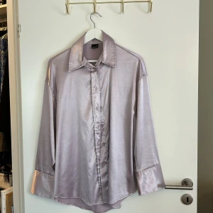Ljuslila satinblus från Gina Tricot - Säljer en superfin ljuslila blus i satin från Gina Tricot. Den har en glansig finish och knappar hela vägen ner. Perfekt för både fest och vardag! 💜
