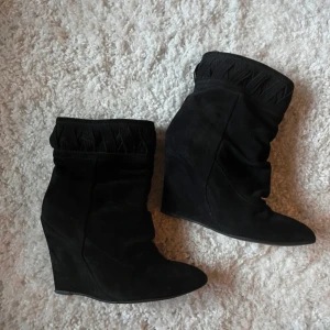 Svarta mockastövletter med kilklack - Snygga svarta stövletter i mocka med kilklack och spetsig tå. Liknar marant. 