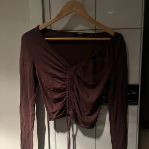 Brun långärmad topp från Bik Bok - Säljer en brun långärmad topp från Bik Bok med knytning framtill. Toppen har en v-ringning. Passar bra till både jeans och kjol.
