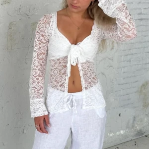 Vit spetsblus med knyt framtill - Säljer en elegant vit spetsblus med knyt framtill. Blusen har långa ärmar och ett vackert blommigt mönster. Perfekt för en stilren look. Pris går att diskuteras. Skriv gärna innan ni trycker på ”köp nu”