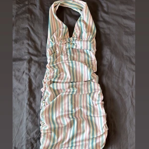 Randig halterneck klänning - Säljer en färgglad randig halterneck klänning med pastellfärger i rosa, blått och vitt. 