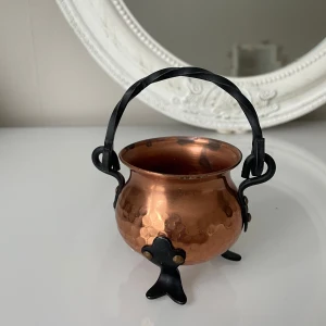 Kopparfärgad dekorativ kittel - Charmig liten kittel i koppar med en hamrad yta och svart handtag av metall . Perfekt som dekorativt inslag i hemmet. Den har tre små ben och en rund form som ger en rustik känsla.höjd 6,05cm.kan möta er i Stockholm utanför Åhléns ,för miljön skull 😊.
