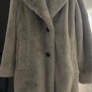 Beige pälsjacka från Zara - Säljer en supermjuk och stilren beige pälsjacka från Zara. Jackan har en klassisk design med knappar framtill och stora fickor. Perfekt för att hålla sig varm och snygg under kyliga dagar. 🧥✨Använd endast en gång!